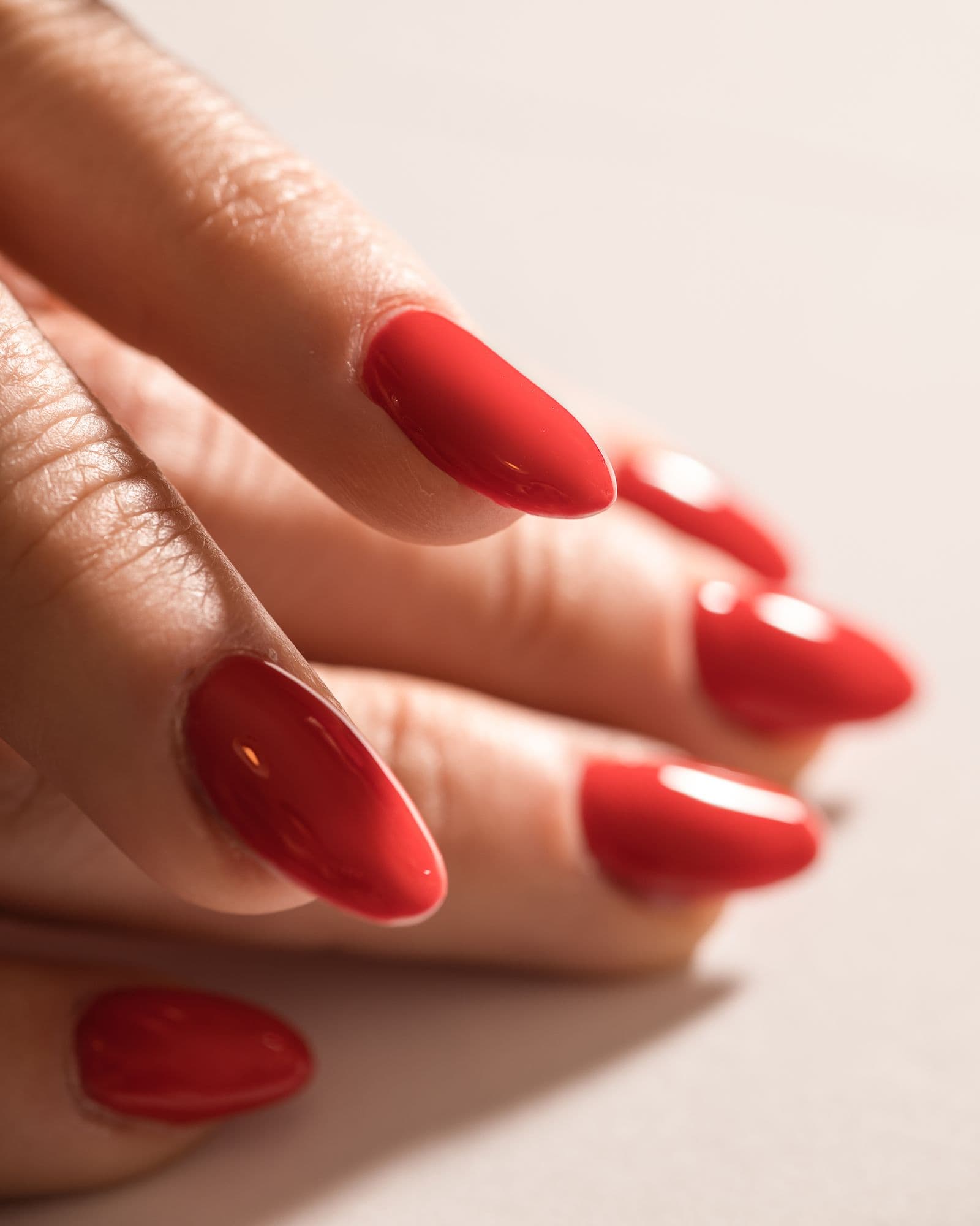 Close-up of glossy red acrylic full set nails