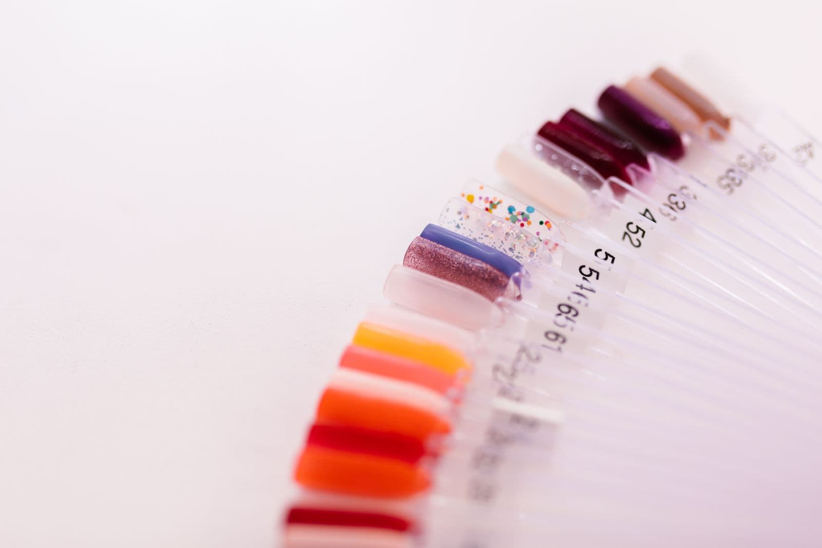 A fanned-out range of vividly coloured dip powder nail swatches